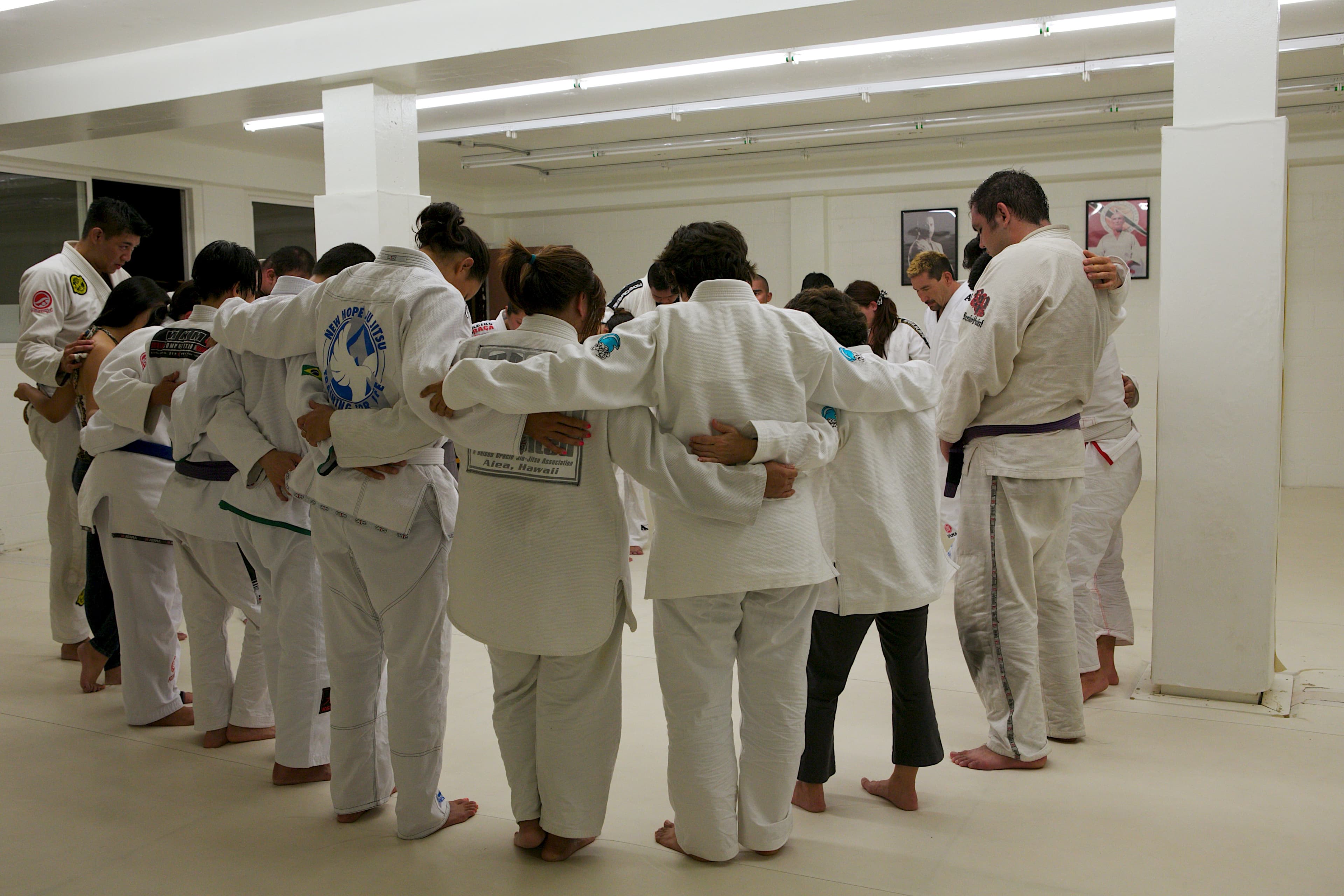 The Sunday class standing in a circle, arms around each other, after training